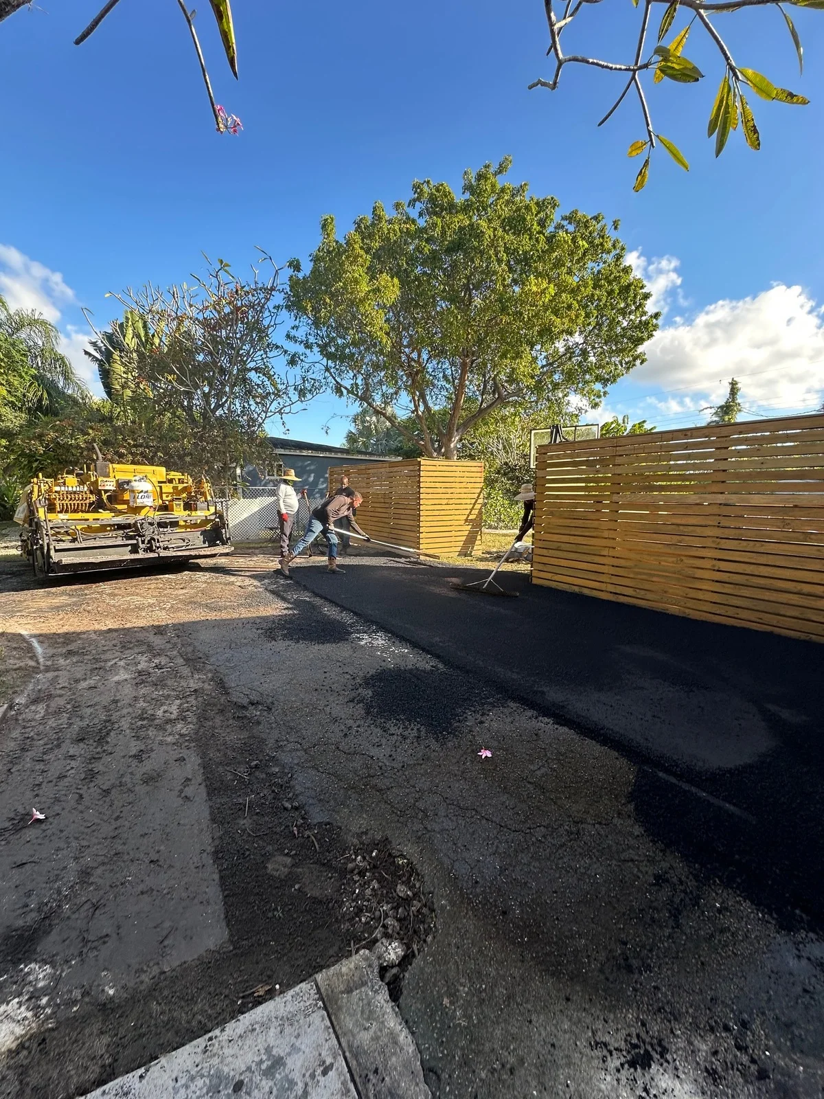Crew raking fresh asphalt behind the paving machine, Miami, FL