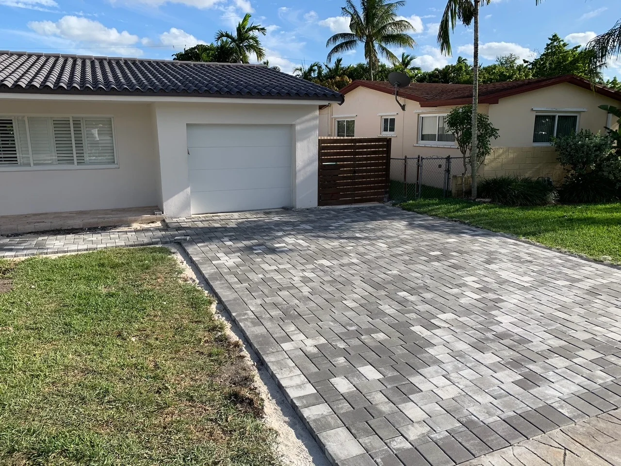 Charcoal and grey pavers laid up to a white garage door beside a wood fence, Miami, FL