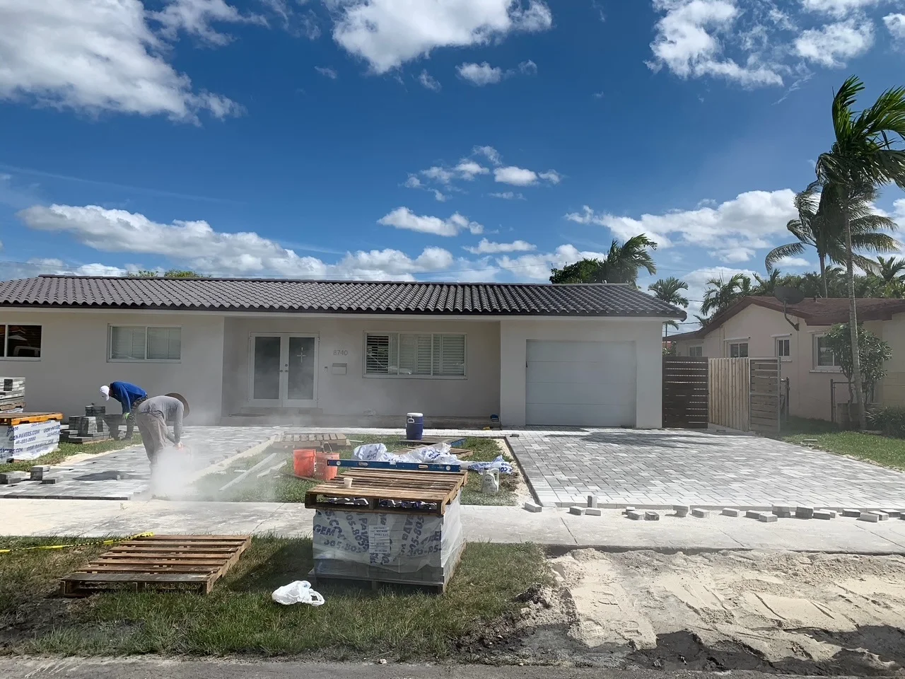 Crew cutting and setting charcoal pavers in front of a house, Miami, FL