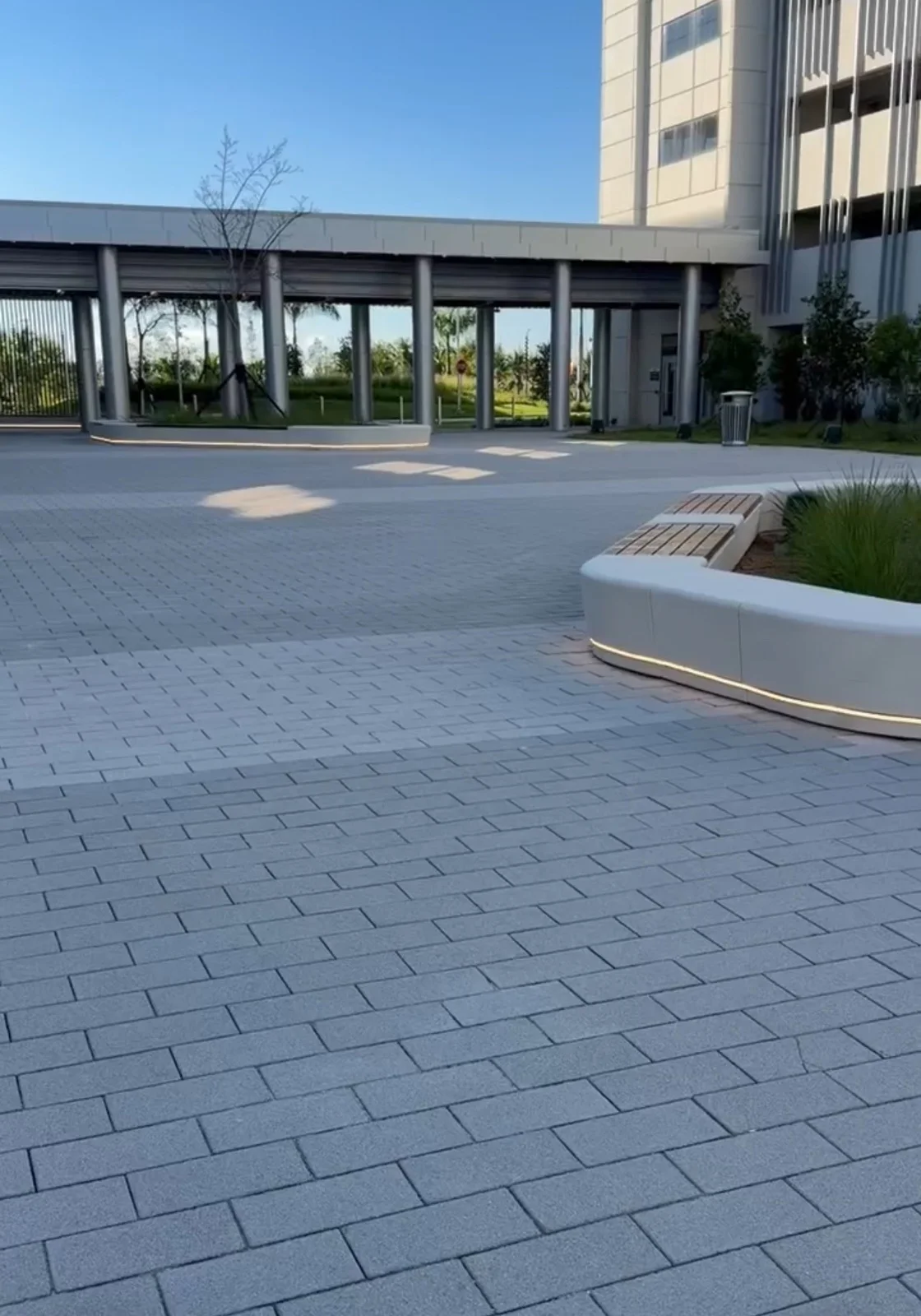 Grey plaza pavers with curved planter benches outside a campus building, Miami, FL