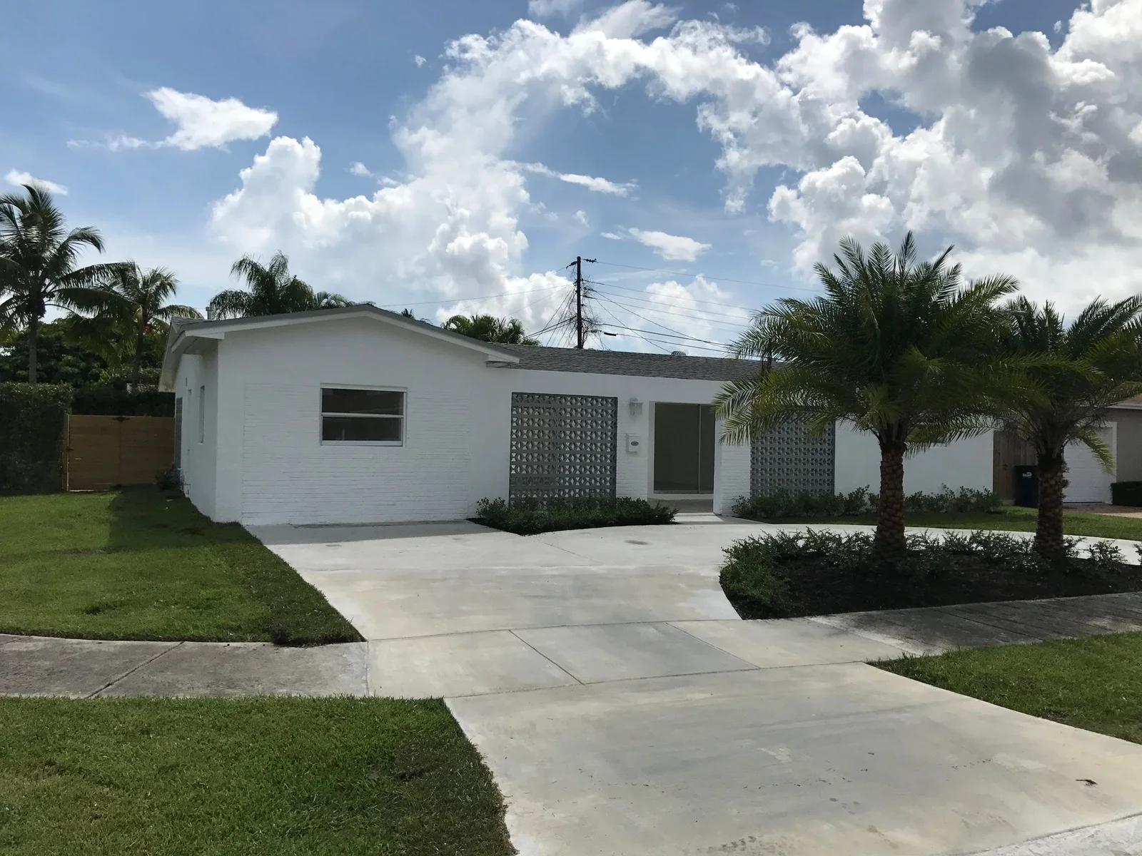 Finished concrete driveway and walkway in front of a white single-story house, Miami, FL