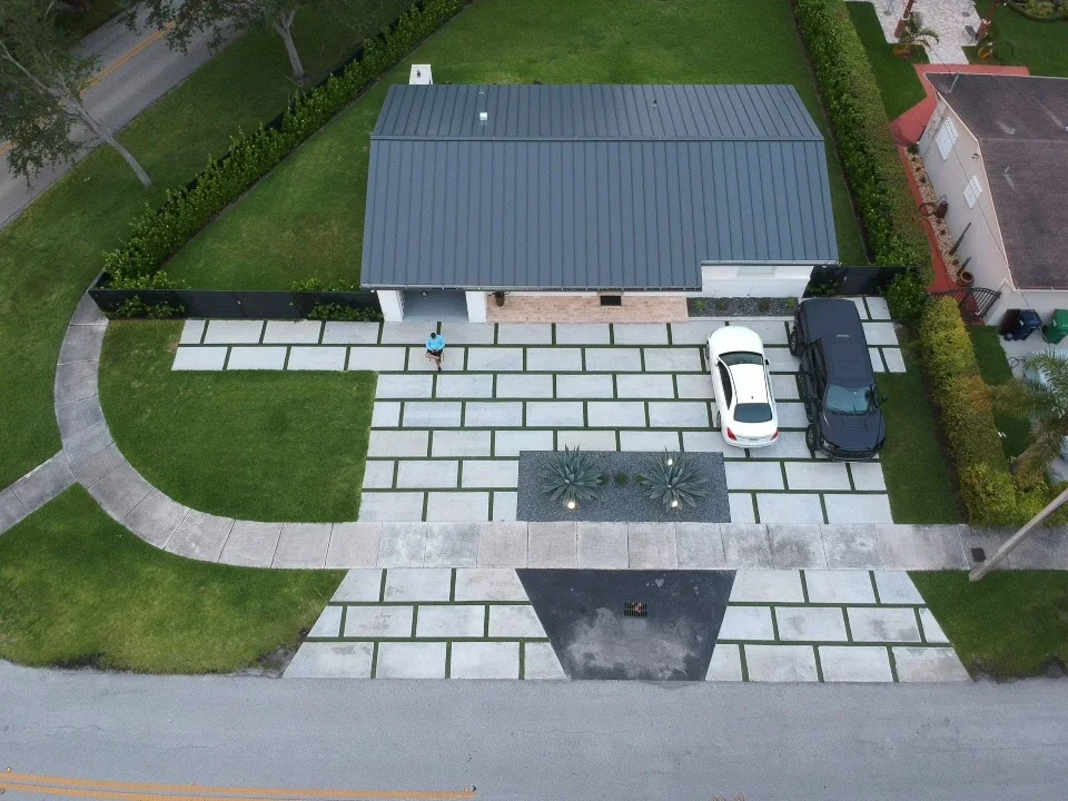 Aerial view of a new concrete slab driveway with turf strips in front of a modern white house, Miami, FL