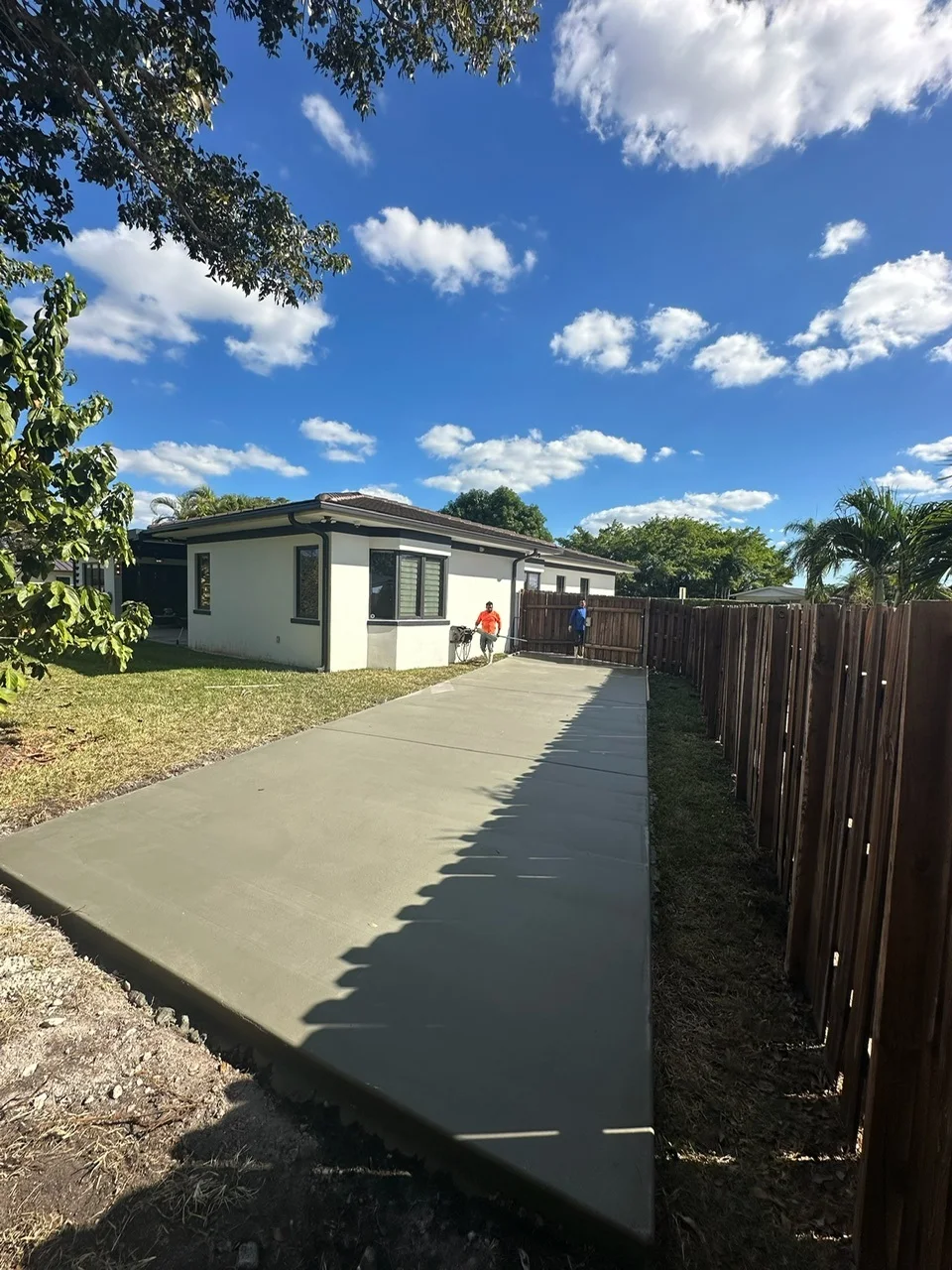 Freshly poured concrete pad running along the side of a house beside a wood fence, Miami, FL