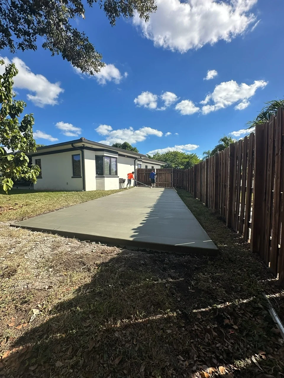 Concrete pad along the side of a house being finished after the pour, Miami, FL