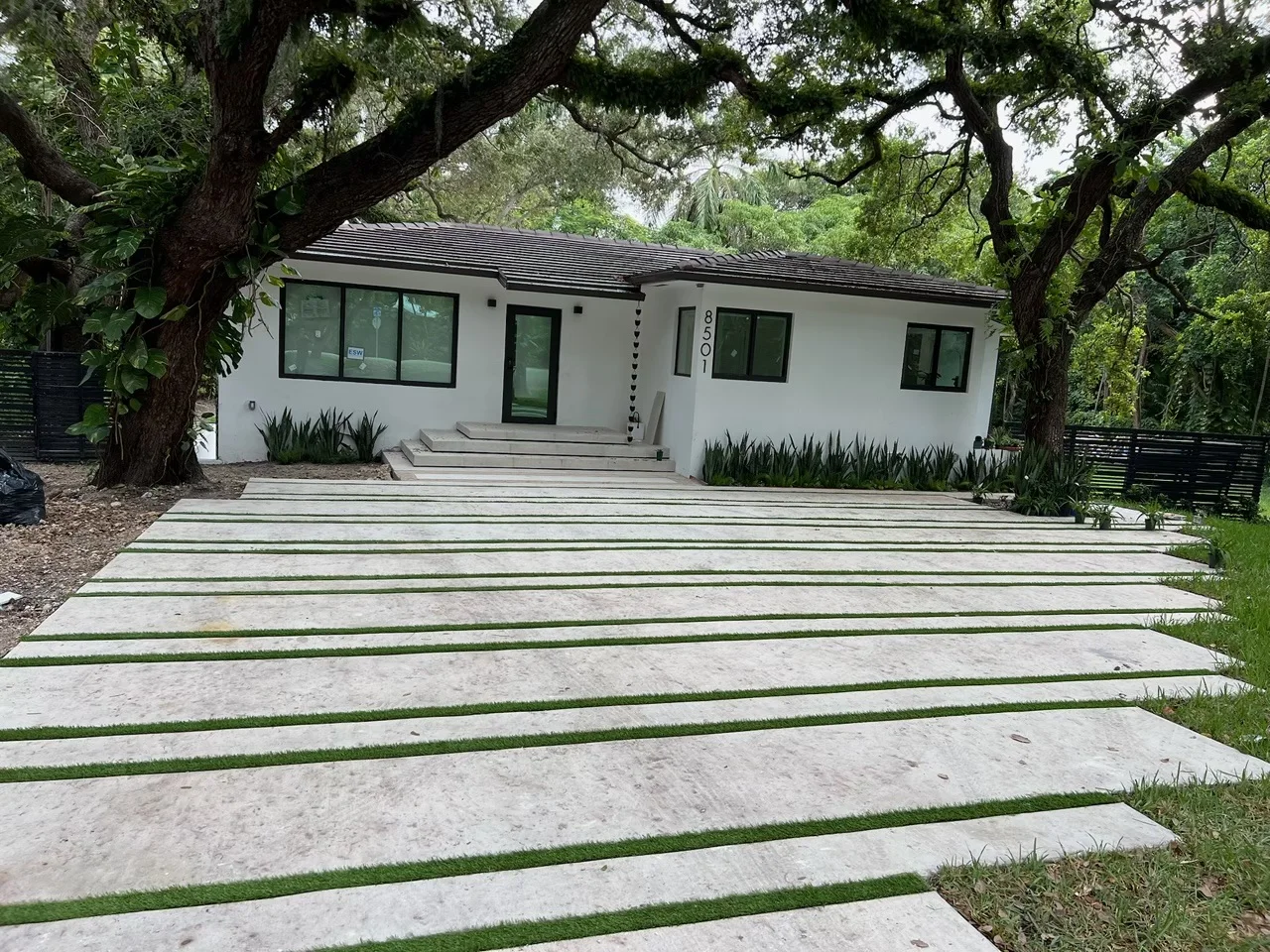 Finished concrete ribbon driveway with a turf strip under oak trees, Miami, FL