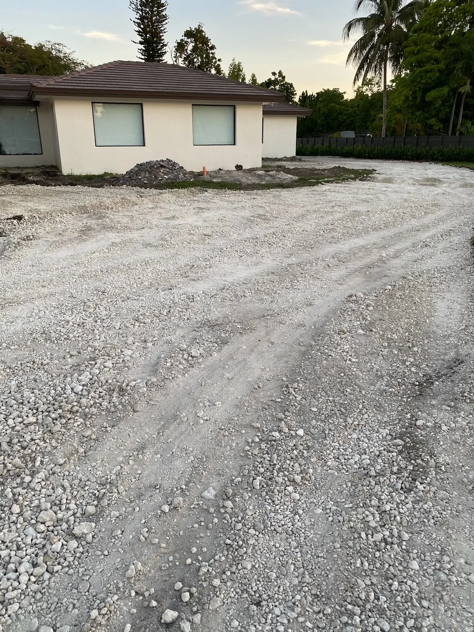 Graded limerock base across a full front drive at dusk, Miami, FL