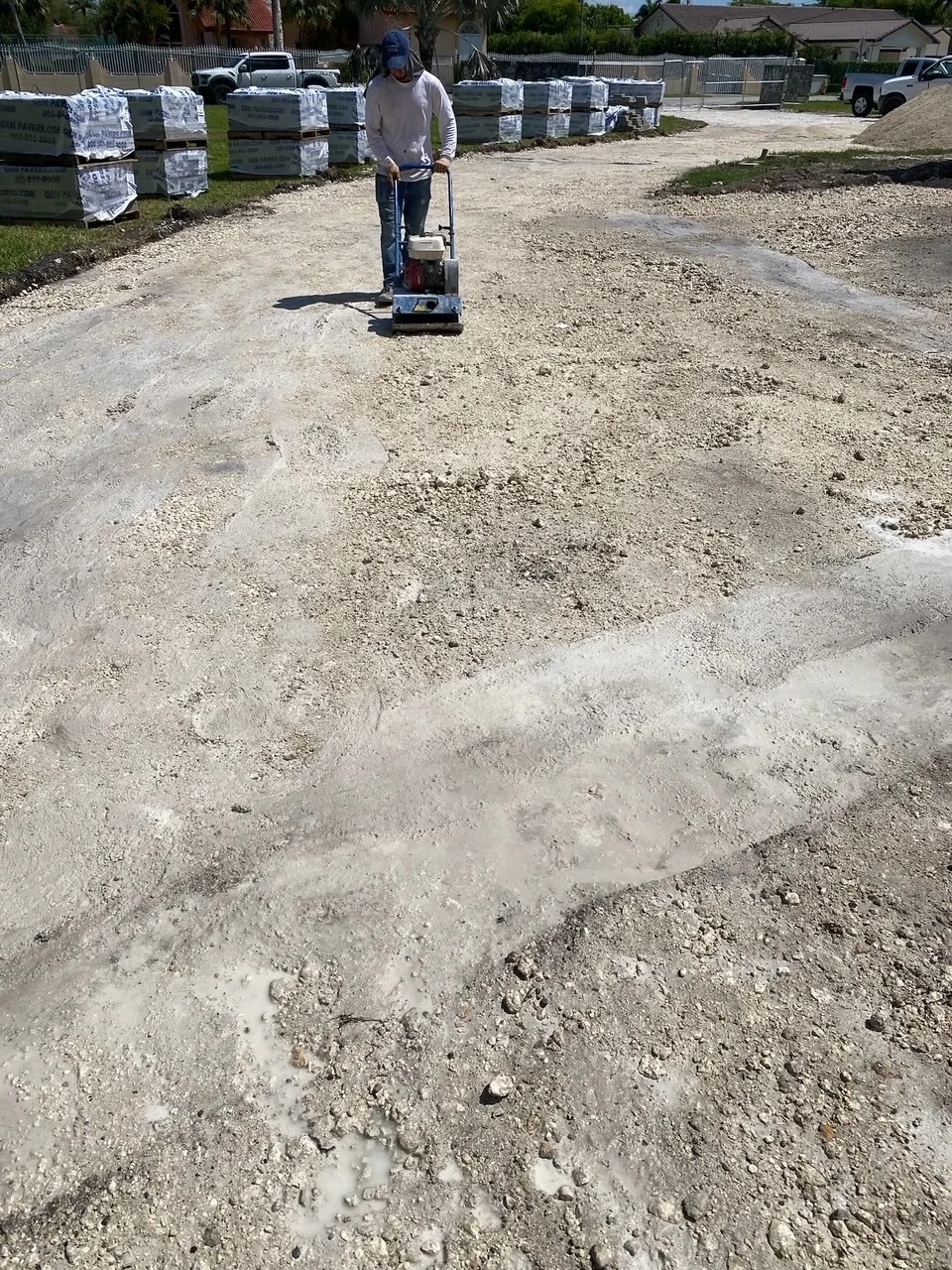 Plate compactor running over the limerock base of a driveway, Miami, FL