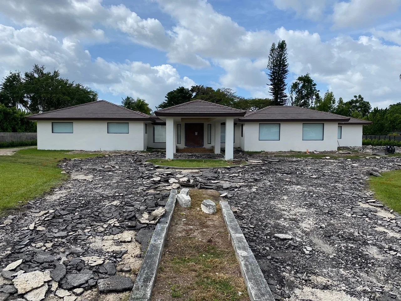 Broken-up asphalt drive in front of a house before its new paver motor court, Miami, FL