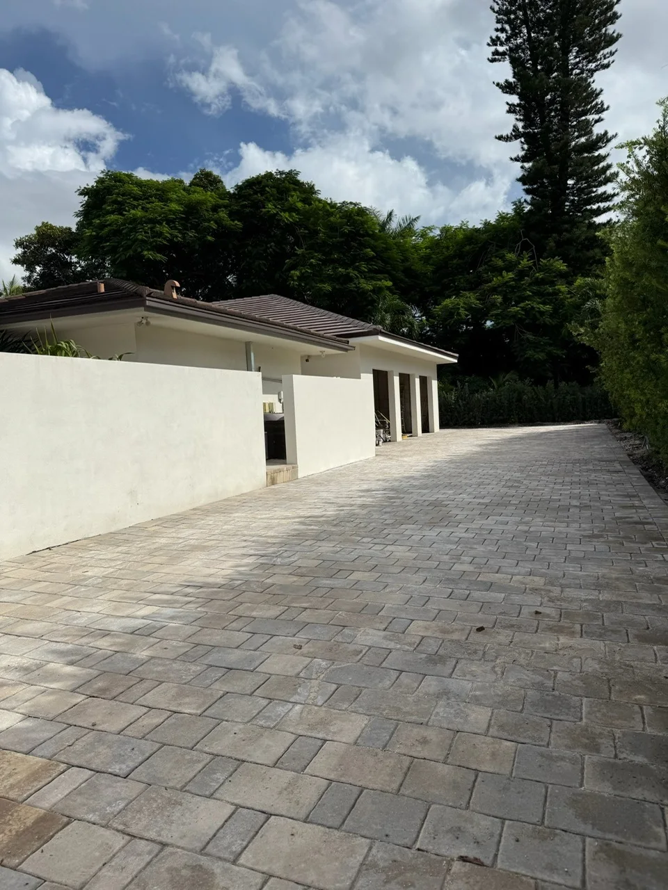 Paver driveway running between a garden wall and a hedge to the garage, Miami, FL