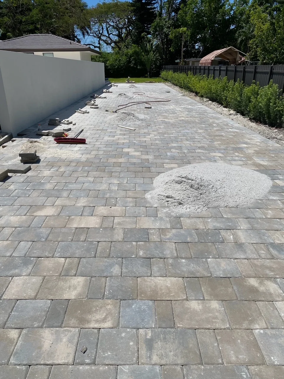 Piles of joint sand spread over a freshly laid paver driveway, Miami, FL