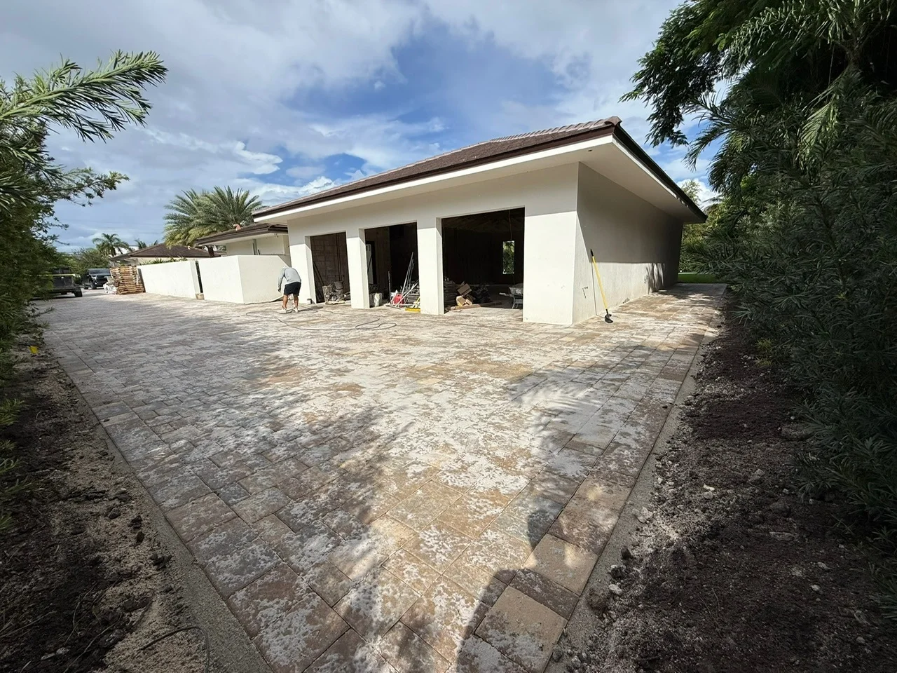 Fresh joint sand hazing a new paver driveway outside a garage, Miami, FL