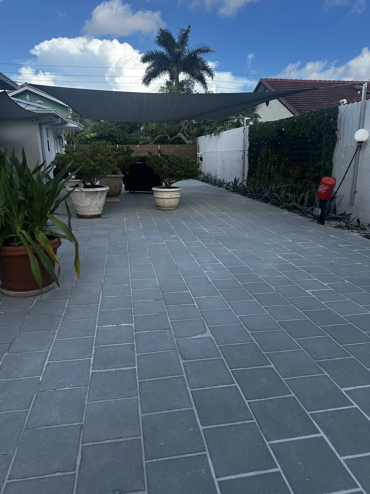 Paver patio laid tight to the house under a shade sail, Miami, FL