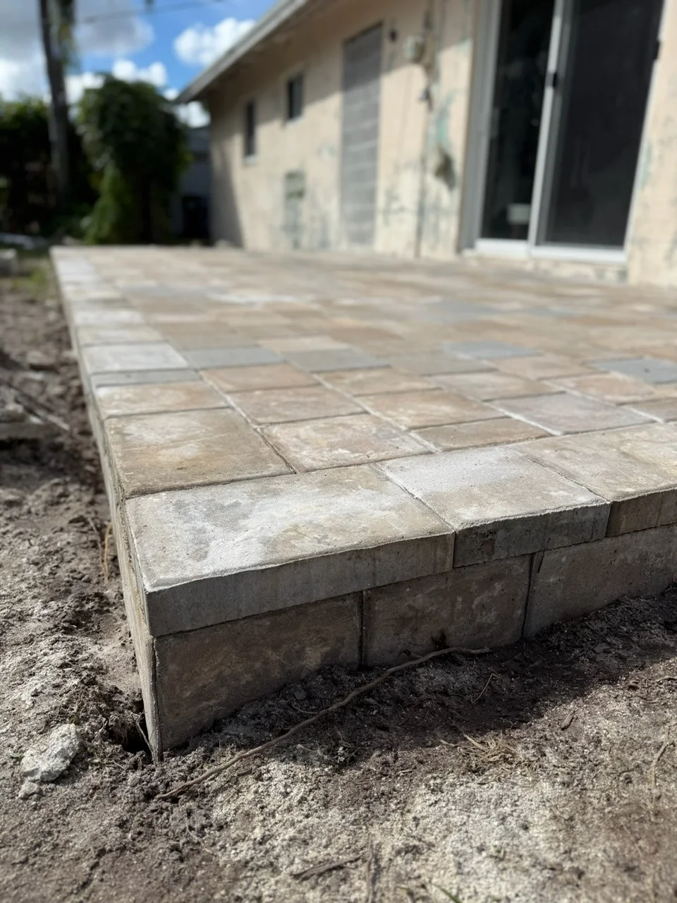 Raised paver patio set on a block edge behind a house, Miami, FL