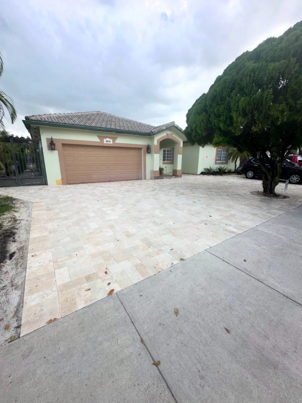 Travertine paver driveway leading to a two-car garage and an entry arch, Miami, FL