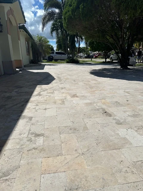 Travertine paver driveway laid in a running pattern beside a planted bed, Miami, FL