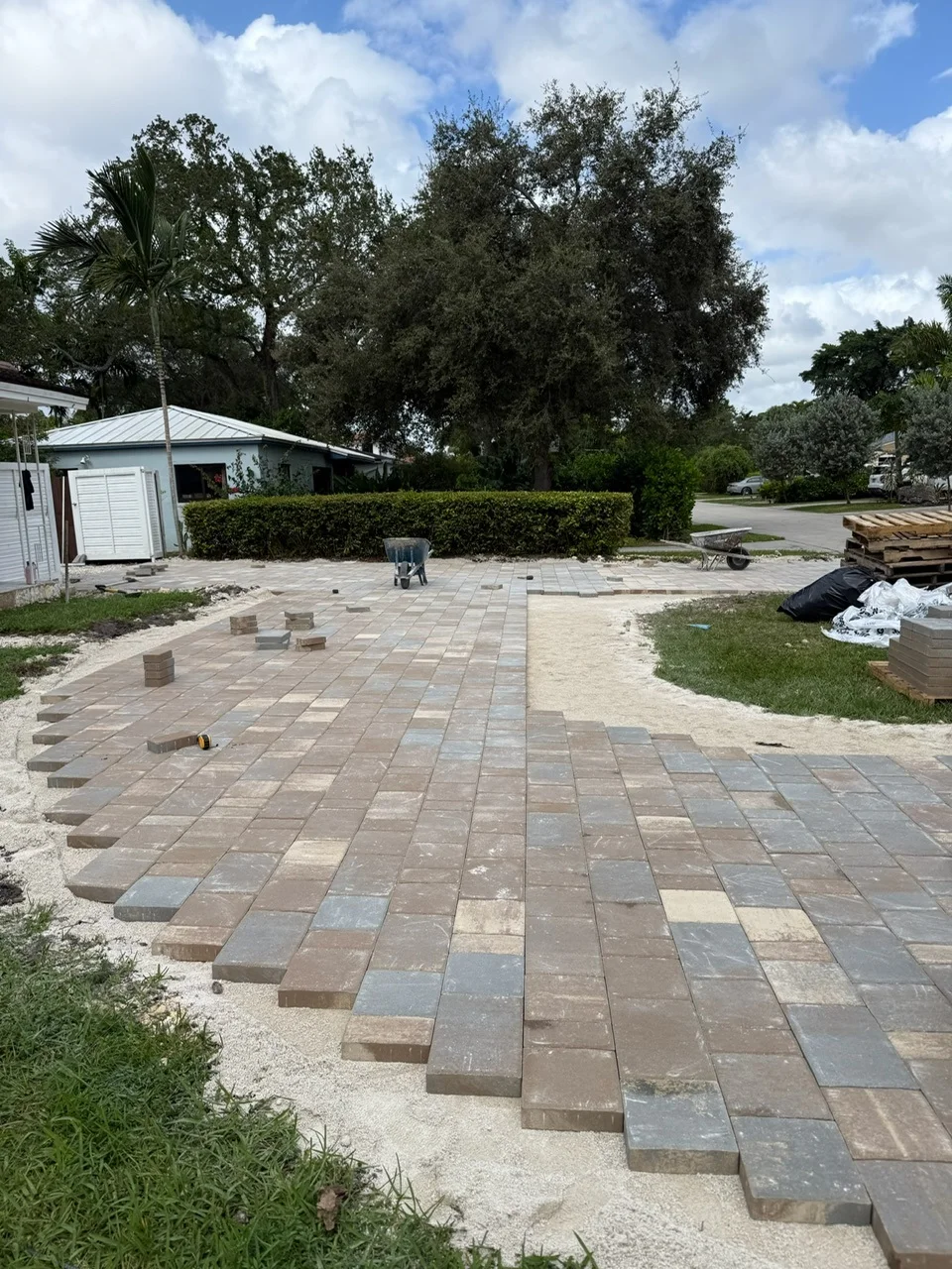 Pavers laid to the street edge with the crew's truck and wheelbarrow on site, Miami, FL